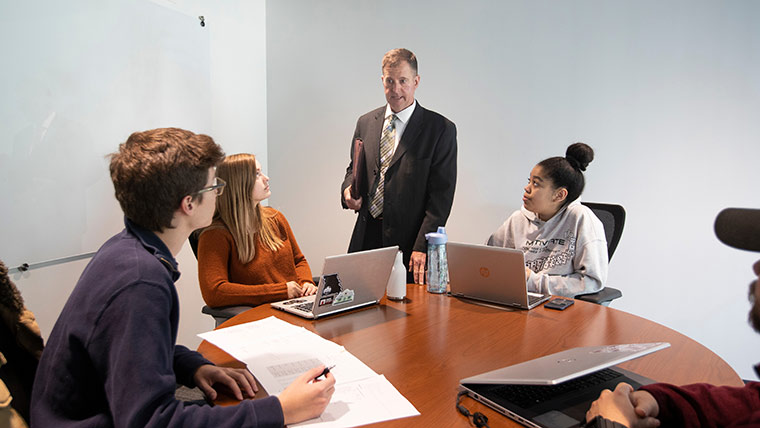 Dr. Wes Scroggins helping management students with class projects inside interview room in Glass Hall.