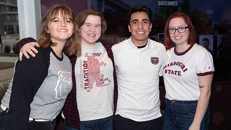 Four smiling Missouri State students all wearing BearWear. 