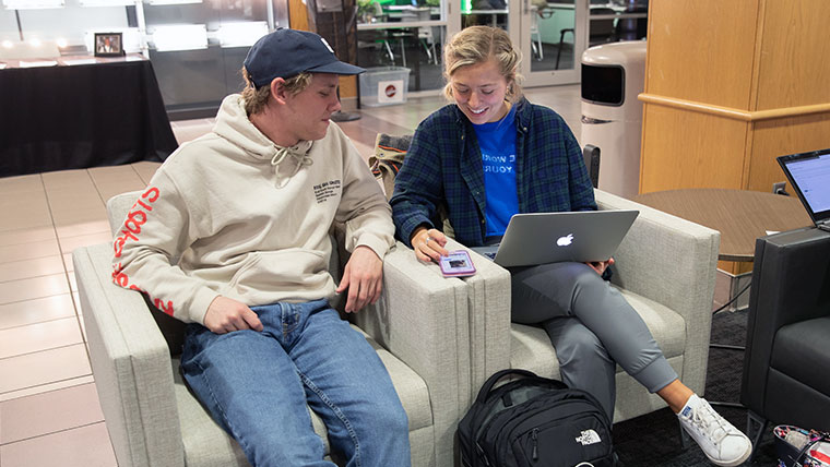 Two Missouri State students reviewing a website on a laptop and a phone. 